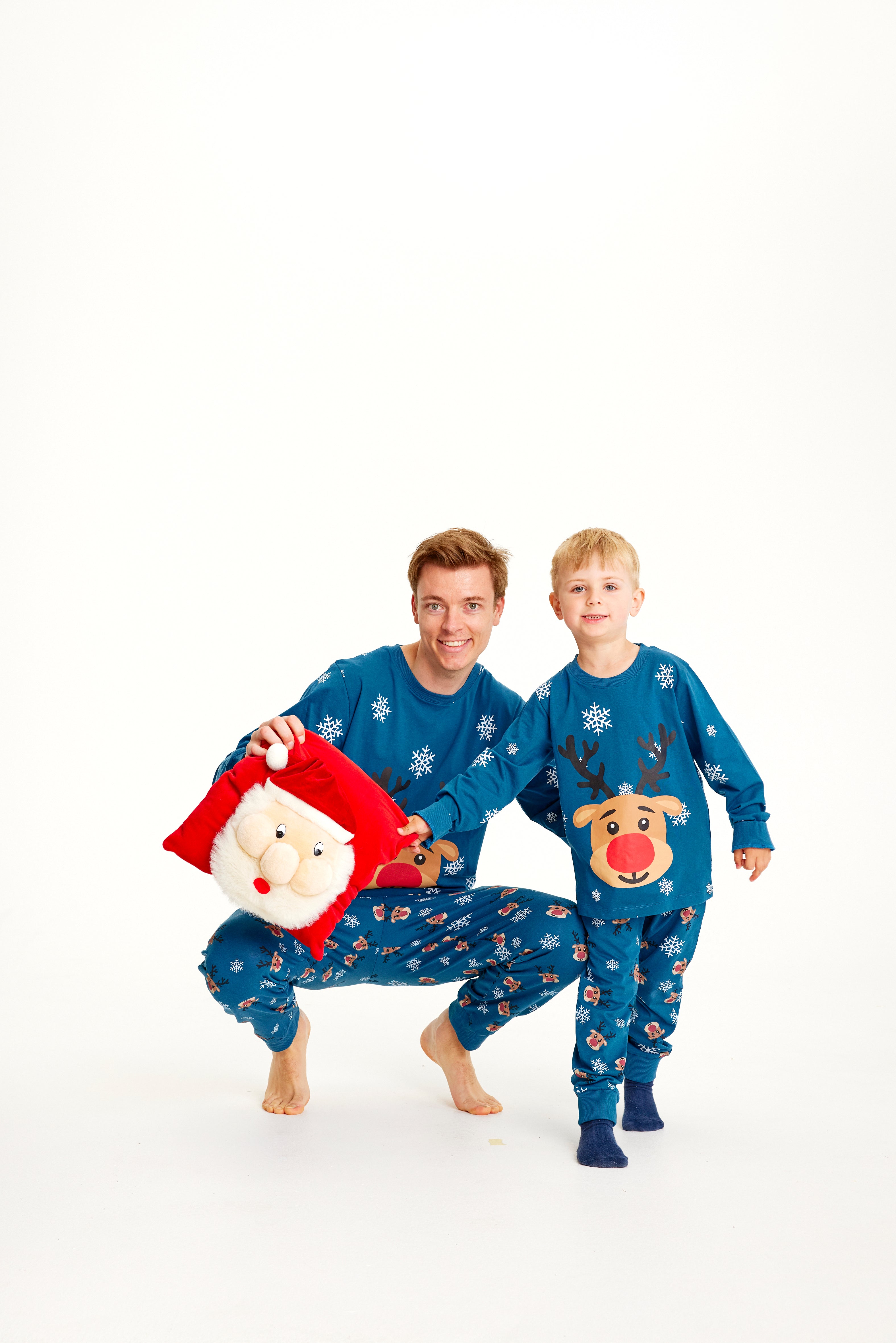 Et barn og en mann poserer iført blå julepyjamas med reinsdyr og snøfnugg.